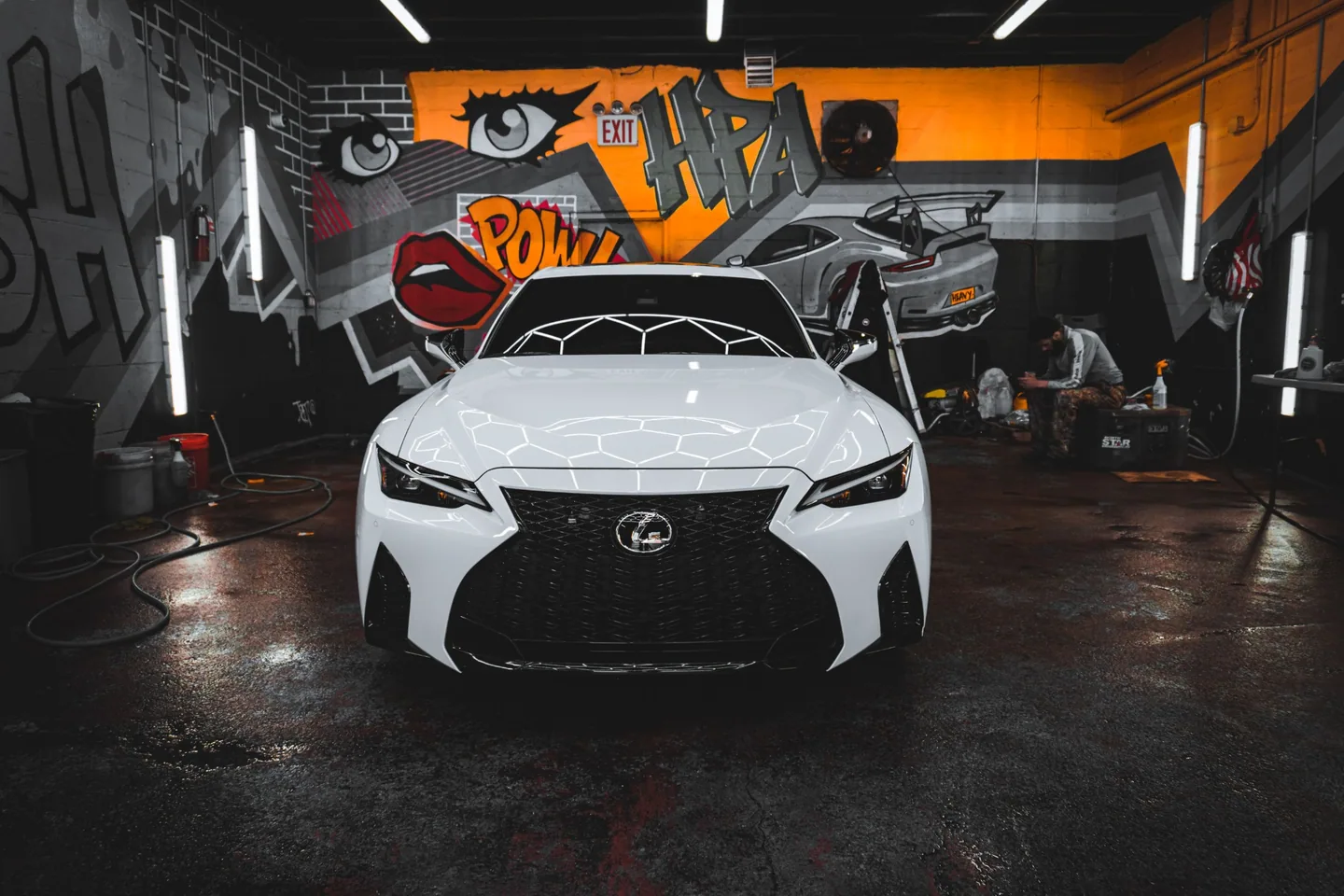 A finished white Lexus reflecting the lights of a professional detailing studio