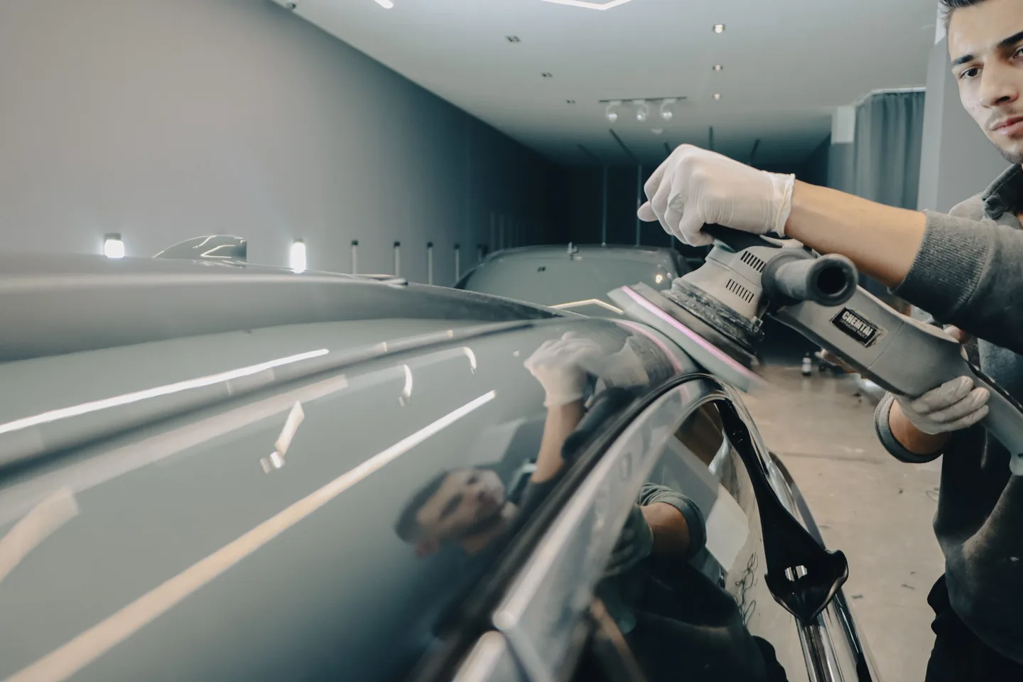 An automotive technician polishing the roof of a vehicle in the workshop