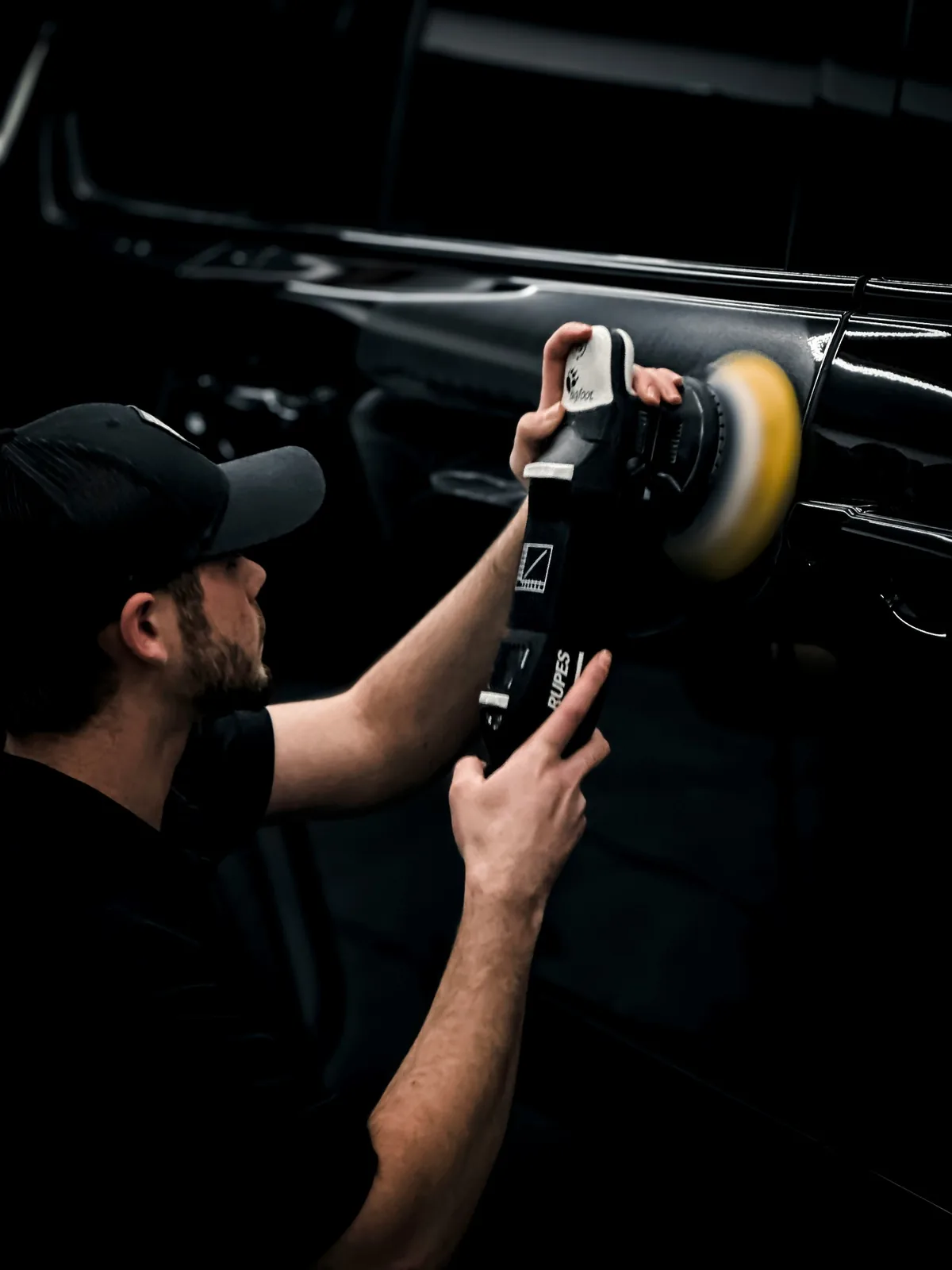 A technician machine-polishing black paintwork