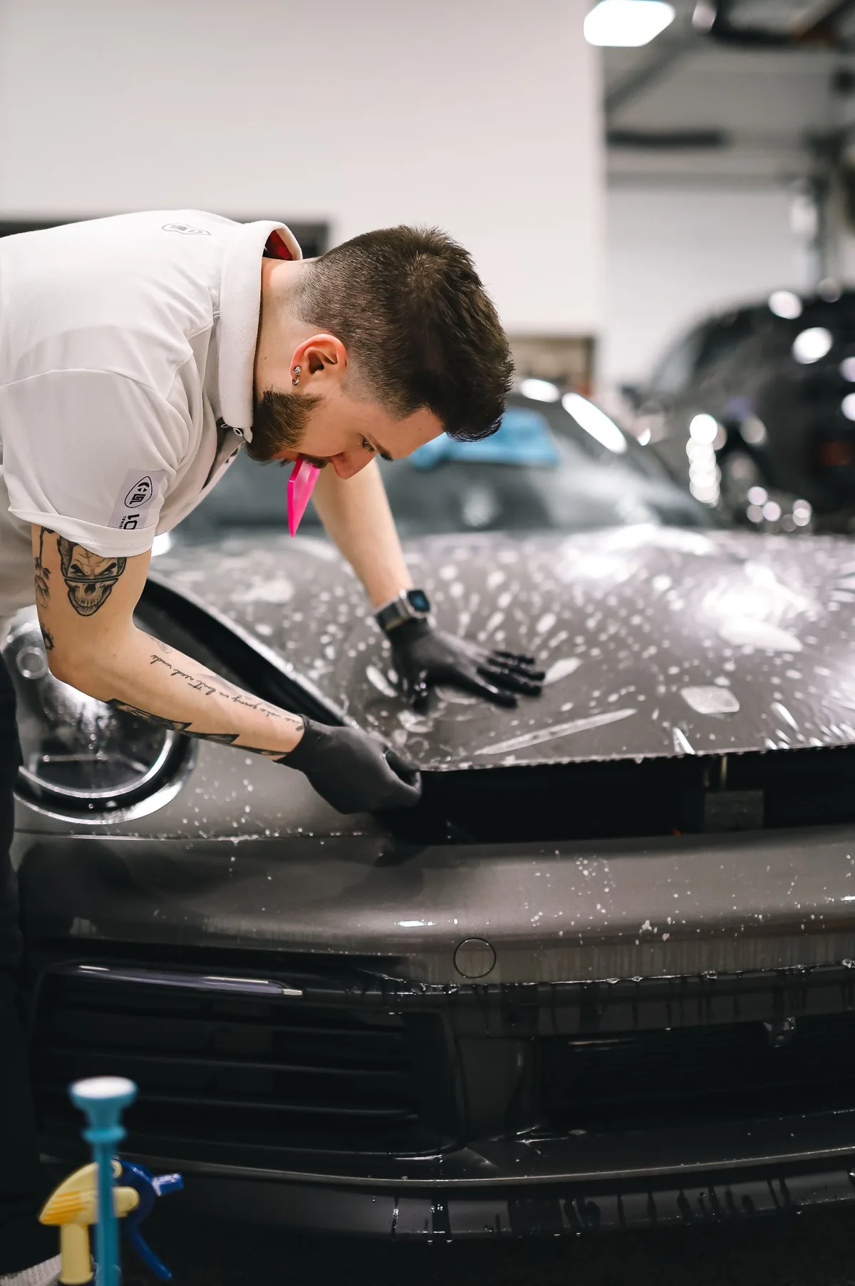 A technician applying paint protection film to a car hood